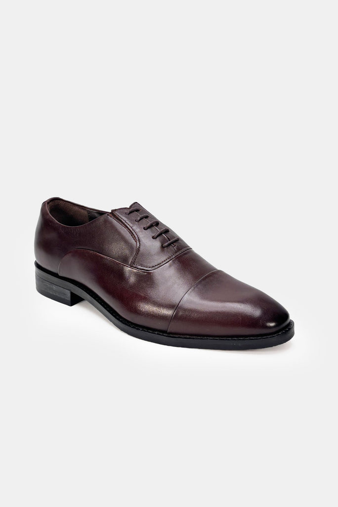 Brown leather dress shoe on a light gray background